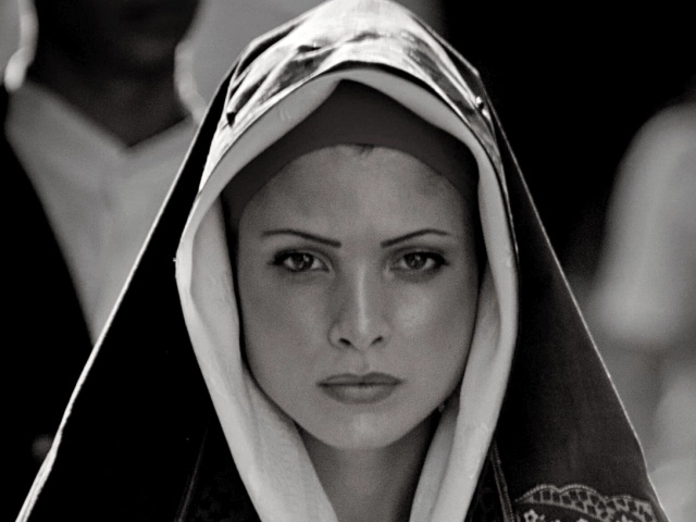 Nell'immagine, in bianco e nero, il primo piano su una donna vestita a tema, con un mantello che le copre anche la testa, per le celebrazioni sarde di Halloween.